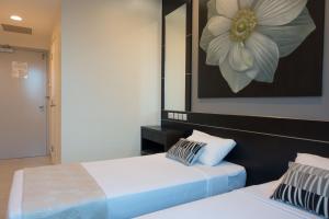two beds in a room with a painting on the wall at Hotel 81 Changi in Singapore