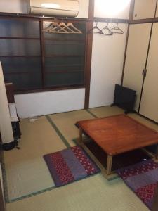 a room with a wooden table and some mats at 昭和レトロタイムスリップ古民家ゲストハウス舞妓まいこ in Kyoto