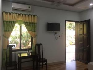 ein Wohnzimmer mit einem Tisch und einem TV an der Wand in der Unterkunft Nhà nghỉ Cát Đằng Hồ Tràm in Hồ Tràm