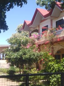 un edificio con flores rosas frente a una valla en Villa Marquez en Camotes Island
