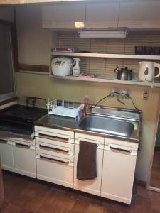 a kitchen with a sink and a stove at 昭和レトロタイムスリップ古民家ゲストハウス舞妓まいこ in Kyoto