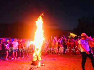 a group of people standing around a large bonfire at Dunhuang ManMan International Desert Outdoor Campground in Dunhuang