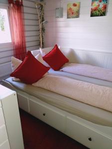 a bed with two red pillows on top of it at Ferienhaus " Silly " am schönen Listersee in Meinerzhagen