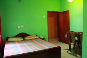 a green bedroom with a bed and a table and chairs at Wijaya Tourist INN in Warakapola