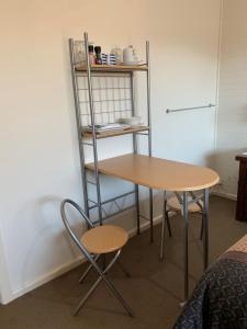 a table and chair in a room with a shelf at Short Stays Gippsland (Newborough) in Moe