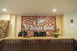 un hombre está parado detrás de una mesa en una habitación en De'Tonga Hotel, en Medan