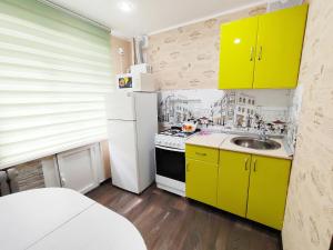 a kitchen with yellow cabinets and a white refrigerator at Апартаменты на Сайдашева 3 in Bugul'ma