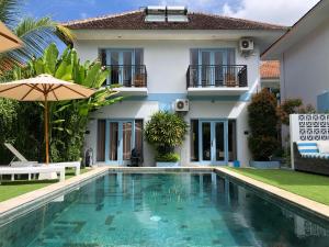 a villa with a swimming pool in front of a house at Gatsby Hotel Hostel in Uluwatu