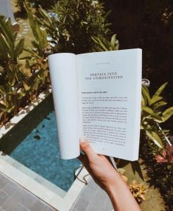 a person holding a book in front of a pool at The Sloth Bali in Canggu
