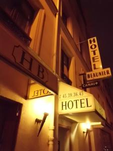 een hotelbord aan de zijkant van een gebouw 's nachts bij Hôtel Beaunier in Parijs