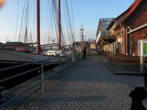 un hombre de pie junto a un muelle con un barco en Altes Strandhus Casa Seestern, en Scharbeutz