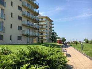 a building next to a grassy field next to a sidewalk at Aqua Apartman Superior in Velence