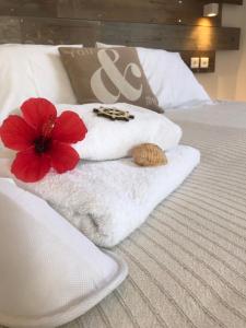 a white towel with a red flower on a bed at Ammos Luxury Studios in Aliki