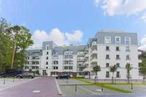 a large white building with cars parked in front of it at Apartamenty Świnoujście - Wyspiańskiego 34e in Świnoujście