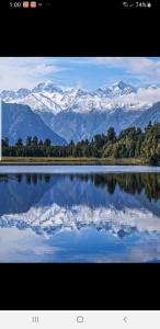 a reflection of snow capped mountains in a lake at The Blackhouse Cottage in Hokitika