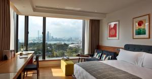 una camera d'albergo con letto, scrivania e ampia finestra di Little Tai Hang a Hong Kong