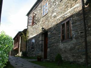 un antiguo edificio de piedra con ventanas y un camino en Casa del forno, en San Martín de Oscos