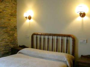 een slaapkamer met een bed en twee lampen aan de muur bij Casa del forno in San Martín de Oscos