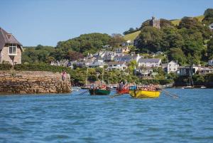 eine Gruppe von Menschen, die in einem Wasserkörper Ruderboote rudern in der Unterkunft Pilchards Cottage in Noss Mayo