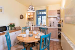 a kitchen with a wooden table and blue chairs at Ferienhaussiedlung Strandperlen Küstenhof 3d (Typ IV) in Wustrow