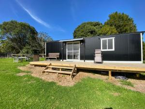 een zwart tiny house met een picknicktafel en een terras bij Cosy cabin to stay even better than Glamping in Pukekohe East