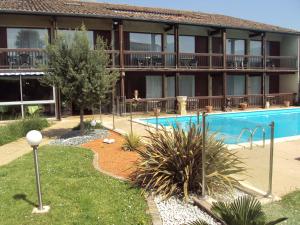a hotel with a swimming pool in front of a building at Le Logis des Cordeliers in Condom