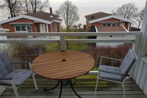 een houten tafel en 2 stoelen op een veranda bij Modern villa i Arild med spektakulär havsutsikt. in Arild