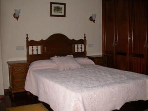 a bedroom with a large bed with a wooden headboard at Casa de Alba in San Martín de Oscos