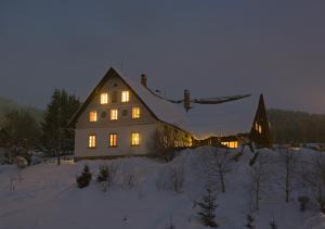 una casa grande con sus luces encendidas en la nieve en Apartmány Chalupa u Floriánka, en Dolní Morava