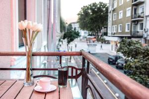 una mesa con una bebida y flores en el balcón en Hotel Art, en Varna