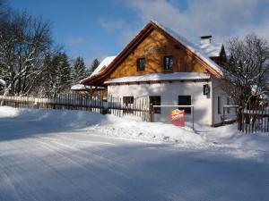 ein schneebedecktes Haus neben einem Zaun in der Unterkunft Pension Klokočí in Sněžné