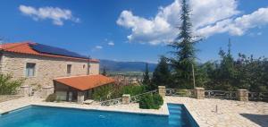 a swimming pool next to a house and a tree at Kyriaki Guesthouse & Suites in Amfikleia