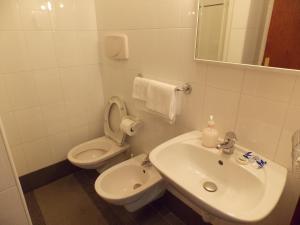 La salle de bains blanche est pourvue d'un lavabo et de toilettes. dans l'établissement Albergo Roma, à Matera