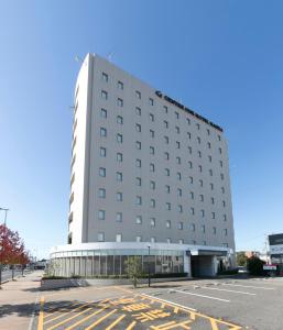 a large white building on a street with a parking lot at Center One Hotel Handa in Handa