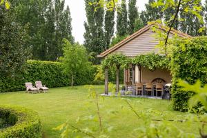 Bassevelde的住宿－Chez Maintje，房屋设有庭院、椅子和桌子