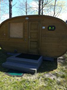 duża drewniana kabina z drzwiami w trawie w obiekcie Imantas nams w mieście Jūrkalne