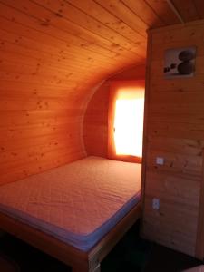 a small bed in a wooden cabin with a window at Imantas nams in Jūrkalne