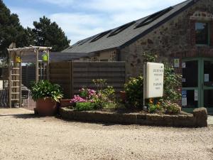 a sign in front of a building with flowers at La Demeure du Perron in Quettehou