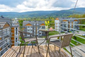 een balkon met 2 stoelen en een tafel met uitzicht bij Apartament Zakątek Górski - 5D Apartamenty in Świeradów-Zdrój