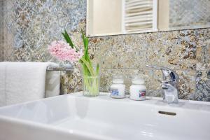 a bathroom sink with a vase of flowers on it at APARTAMENT GOLD in Bielsko-Biała