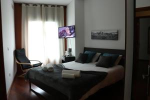 a bedroom with a bed and a chair and a window at Metro Heroismo Residence in Porto