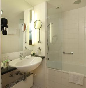 
a white sink sitting under a mirror in a bathroom at Lindner Hotel Dom Residence in Cologne

