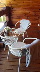 two wicker chairs and a table on a porch at Viesu namiņš Dālderi in Varakļāni