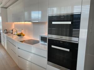 una cocina con armarios blancos y horno negro en Luxury Penthouse Zurich en Zúrich