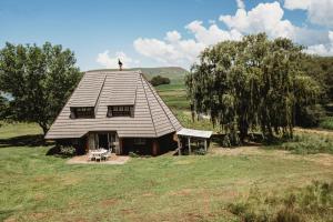 a small house with a roof on a field at Valley Lakes CHALETS in Underberg