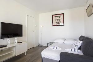 a white living room with a bed and a flat screen tv at Studio Arché - Welkeys in Biarritz +4 photos