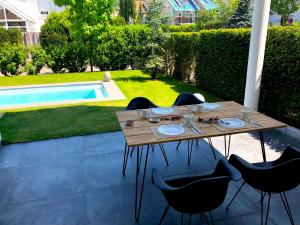 a wooden table and chairs in a backyard with a pool at Dreamapartment La Vigna Living mit eigenem Aussenpool & Sauna - Weil am Rhein in Weil am Rhein