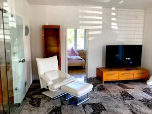 a living room with a white chair and a television at Dreamapartment La Vigna Living mit eigenem Aussenpool & Sauna - Weil am Rhein in Weil am Rhein