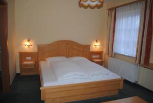 a bedroom with a bed with white sheets and two lights at Gasthof Knappenwirt in Tamsweg