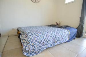 a bed with a blue and white comforter in a room at Maisonnette avec terrasse à 50m de la plage in Luc-sur-Mer
